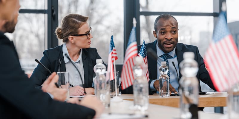 selective focus of attractive businesswoman looking at african american diplomat