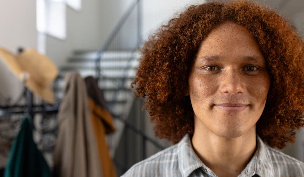 Portrait Of Happy Caucasian Man With Curly Hair Over Stairs At Home. Domestic Life And Lifestyle, Unaltered.